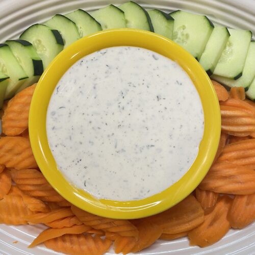 Low Sodium Ranch dressing served in a yellow bowl with sliced cucumbers and carrots